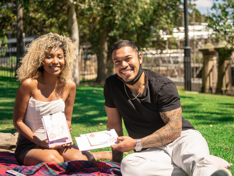 Couple sitting in a park showing their watercolour paintings